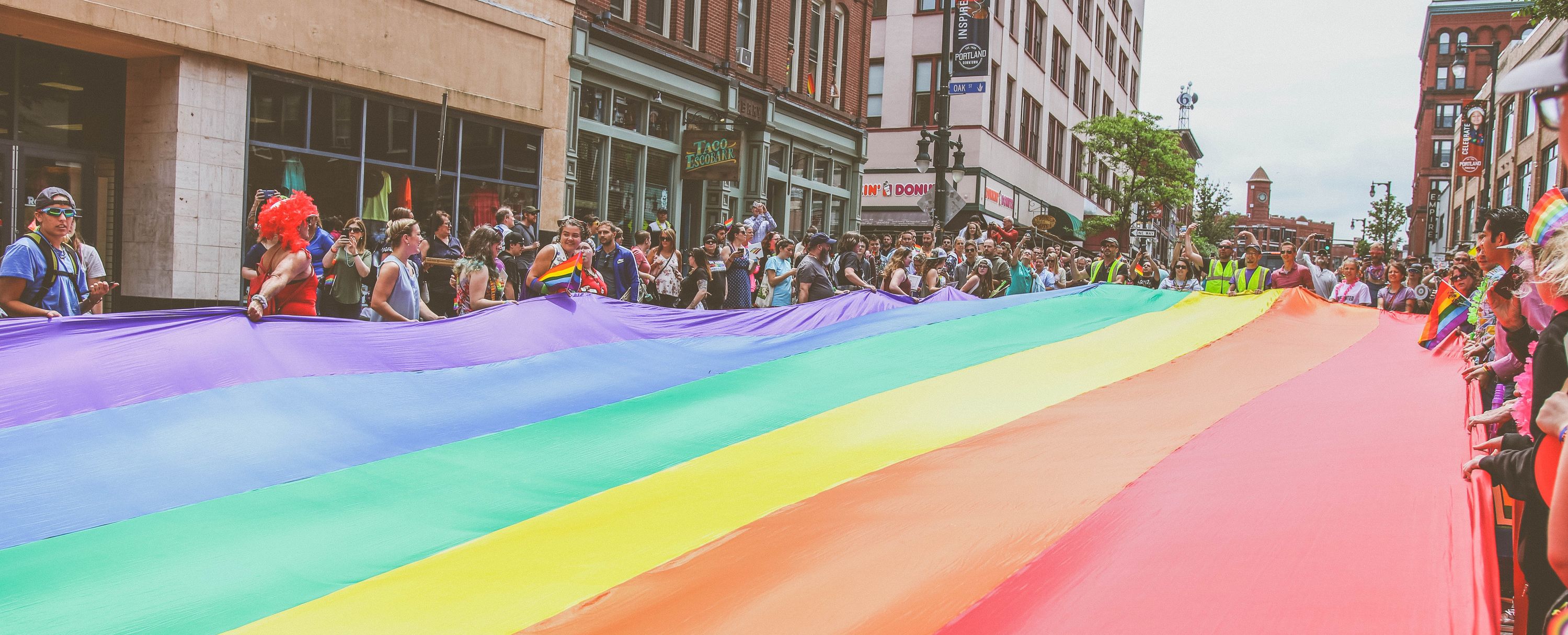 Portland, Maine residents carry the large rainbow flag down Congress Street during the annual Pride parade