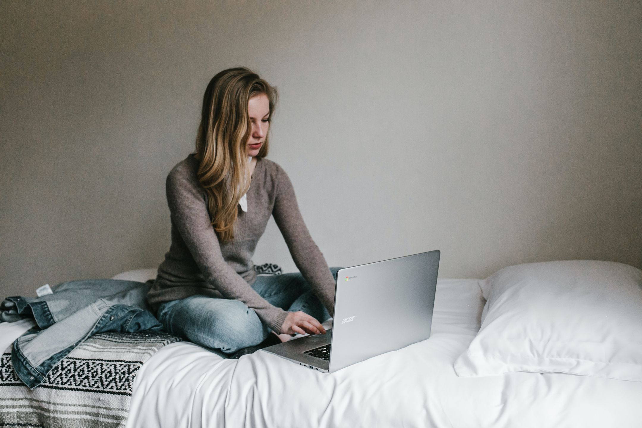 Woman on laptop on bed -- Toucan